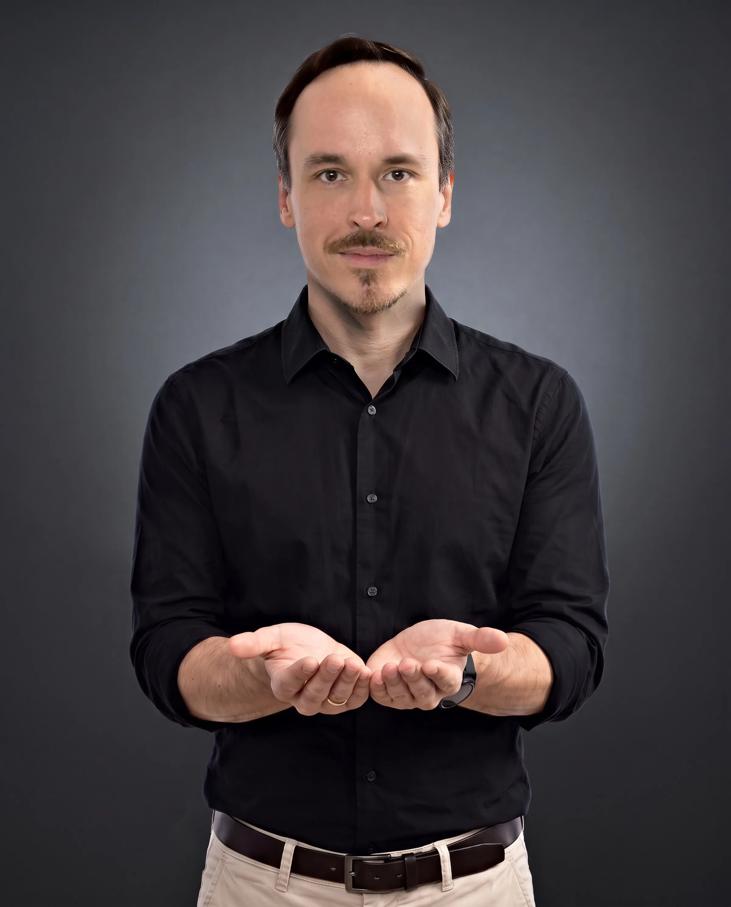 Krystian Gadomski in a graphite studio, holding out his open palms